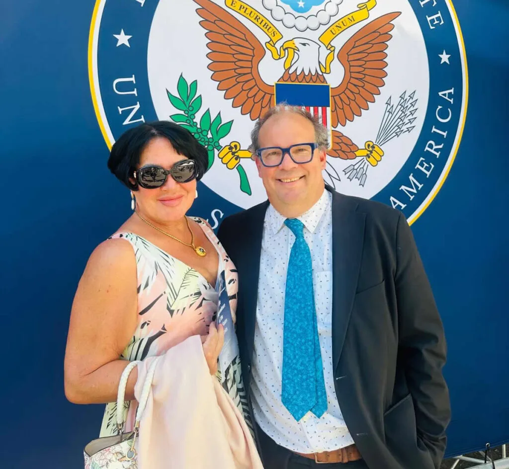 Annie Schur and Robert Schur before the Great Seal of the United States at the Department of State's 250th Independence anniversary reception in Oslo.