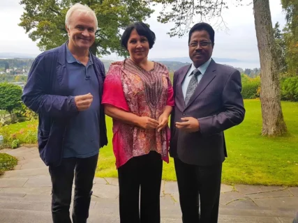 Annie Schur, Martin Alfsen, and Indian Ambassador to Norway Debraj Pradhan in a diplomatic garden setting.
